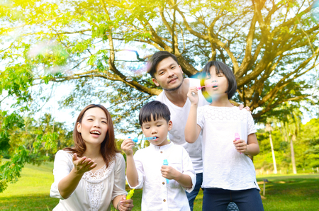 Asian family blowing bubbles in the parkの写真素材