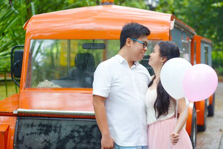 Asian girl holding balloons and looking at her boyfriendの写真素材