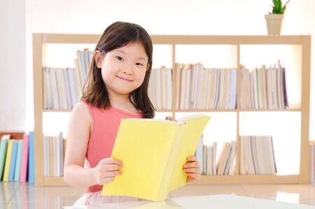 Lovely asian child reading book at homeの写真素材