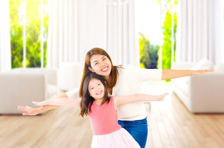 Asian woman and daughter open their arms in the living roomの写真素材