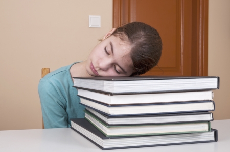 Young woman sleeping on books with open mouthの写真素材