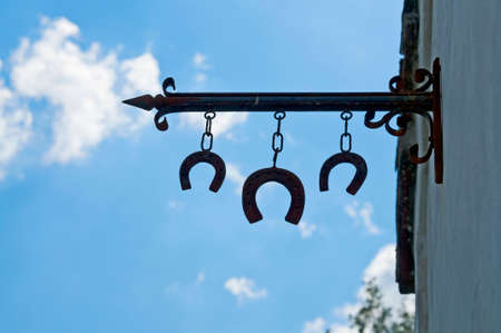 Three horseshoe blacksmith sign hanging with nice sky at backgroundの写真素材