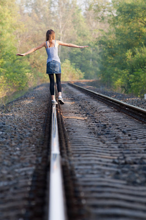 One teen girl balancing away on rail at sunset with trees behind herの写真素材