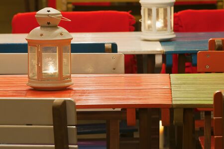 On different colorful wooden tables standing lighting candle lanternsの写真素材