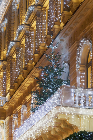 Building facade with light string decoration at night with Christmas tree on the balcony, door and large windowの写真素材