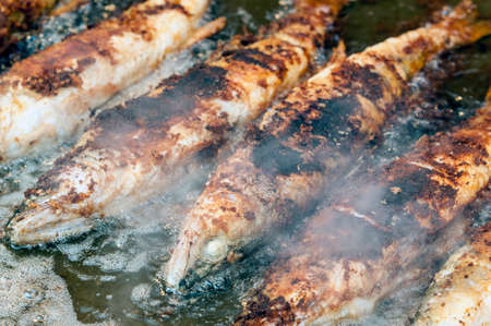 In a large pan lie next to each other some whole fried fishes with some steam aroundの写真素材