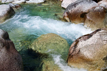 Creek water rushing with large rocks at sunny day