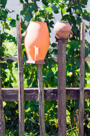 Jugs on old wood fence with green plant in backgroundの写真素材