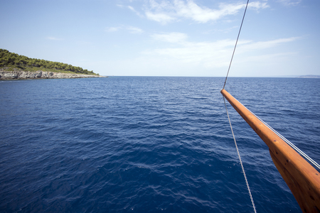 Ship floating on blue water and prow pointing to islandの写真素材