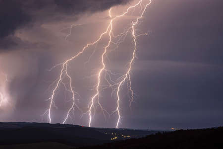 Huge detailed storm lightnings at night with landscapeの写真素材