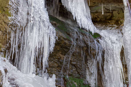 Small blurred motion waterfall on the rocks with icicles aroundの写真素材