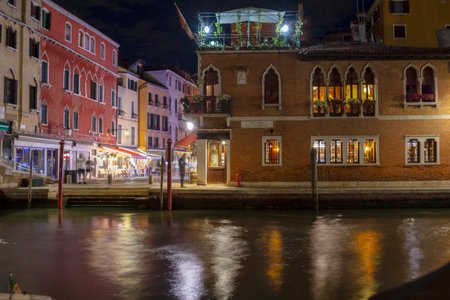 Old houses and empty canal in foreground with night lights, Venice, Italyの写真素材