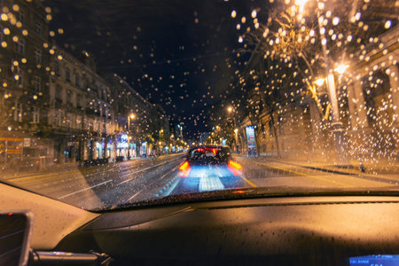 Night car traffic is visible through a raindrop windshieldの写真素材
