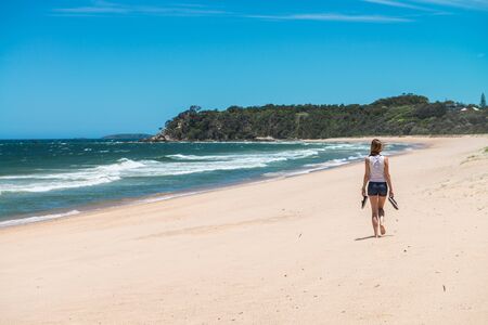 Woman walking along a completely deserted beach strip on the eastern coast of Australia.のeditorial素材
