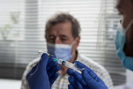 Doctor giving a senior woman a vaccination. Virus protection. COVID-2021.の写真素材