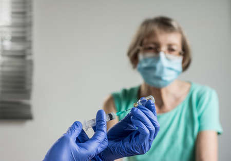 Doctor giving a senior woman a vaccination. Virus protection. COVID-2021.