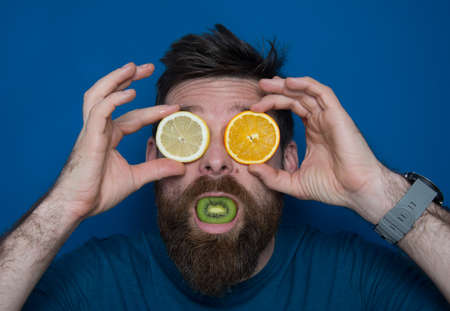 Man poses with kiwi and lemons on his faceの写真素材