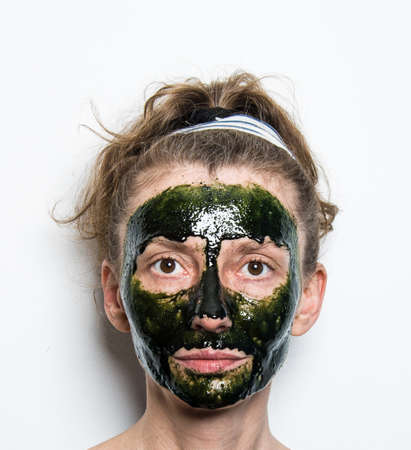 Woman face with spirulina skincare mask. Isolated, white background. Skin spa treatment concept.の写真素材