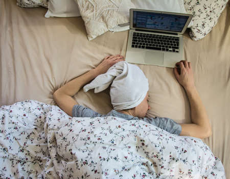 Woman in bed with laptop using internet in online serviceの写真素材