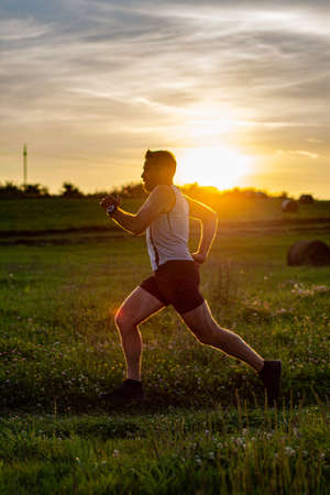sunset and running young man . man running on meadow at sunset active lifestyleの写真素材