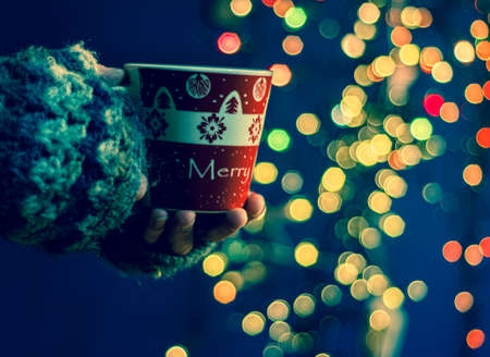 Woman holding mug with mulled wine or hot chocolate at christmas market.の写真素材