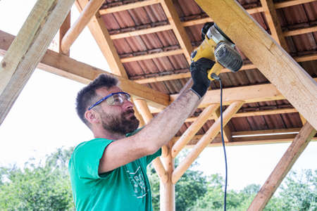Worker grinds the wood of angular grinding machine at his workstation . Solid as the wood we work withの写真素材