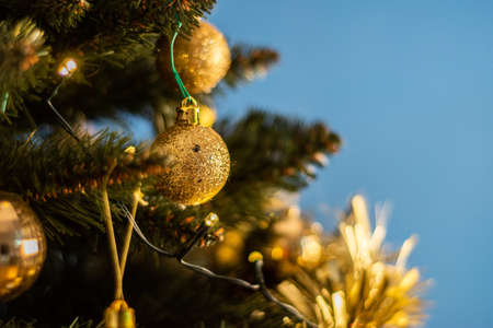 Closeup of a decorative ornament hanging from the Christmas tree covered with lights.の写真素材