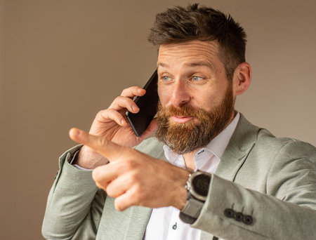 Portrait of successful businessman in office, talking smartphones.の写真素材