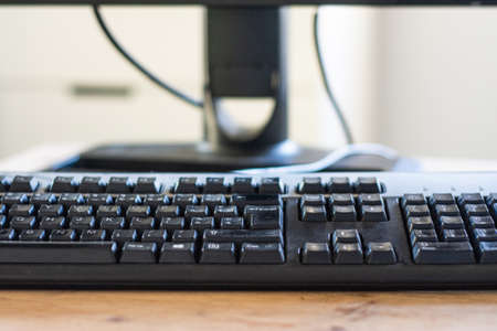 close up view of computer keyboard at table with computer mouse and laptop on blurred backgroundの写真素材