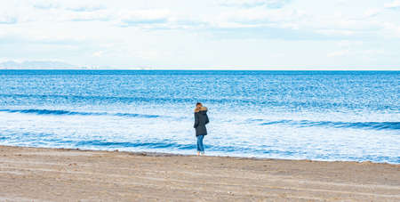 Rear View Of Person Standing At Sea Shore Against Skyの写真素材
