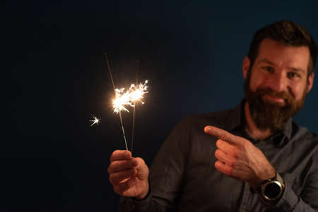 Caucasian man playing with sparklers celebration and festive party conceptの写真素材