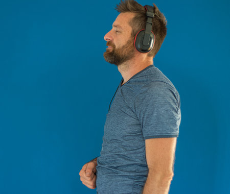 Young Man Listening Music Against Blue Background