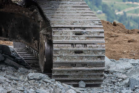 Close up detail with chain tracks of a bulldozer on a demolition site. Backhoe wheel located on site for constuctionの写真素材