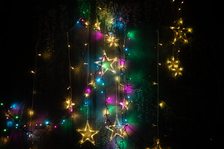 Beautiful colorful Christmas star lights hanging against a dark background. Perfect for holiday...