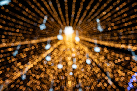 Abstract golden bokeh light tunnel with radiating, defocused festive lights. A warm, glowing...
