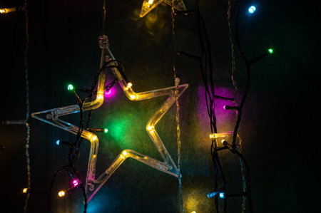 Beautiful colorful Christmas star lights hanging against a dark background. Perfect for holiday...