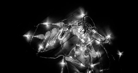 Warm white LED string lights glowing softly on a wooden surface. Perfect for Christmas, New Year, or cozy home decor themes. Ideal for holiday backgrounds, festive designs, and interior decoration concepts.の写真素材