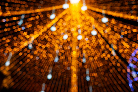 Abstract golden bokeh light tunnel with radiating, defocused festive lights. A warm, glowing background perfect for holiday, Christmas, celebration, and decorative design projects.の写真素材