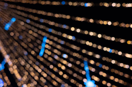 Abstract golden bokeh light tunnel with radiating, defocused festive lights. A warm, glowing background perfect for holiday, Christmas, celebration, and decorative design projects.の写真素材