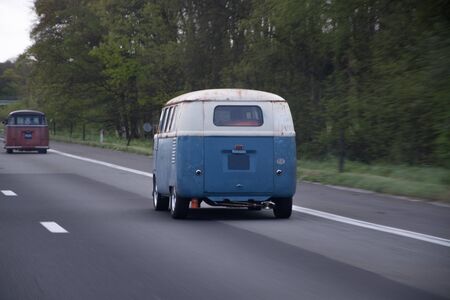 Old blue and white car driving down the highway