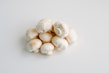 White champignon mushrooms and sliced mushrooms isolated on light backgroundの写真素材