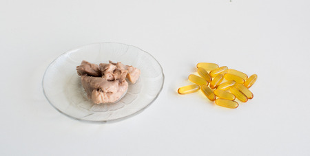 Smoked raw cod liver on a plate side by side capsule form nutritional supplements of fish oilの写真素材
