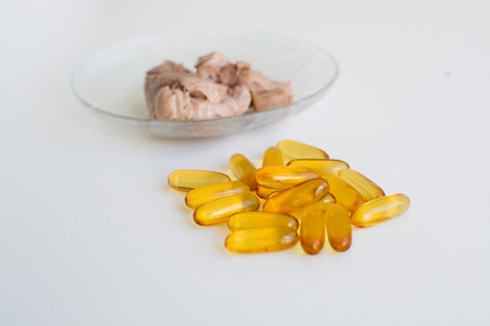 Smoked raw cod liver on a plate side by side capsule form nutritional supplements of fish oilの写真素材