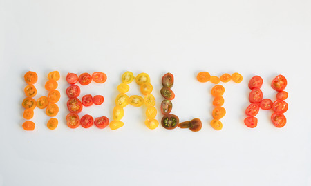 The word health written in slices of cherry cocktail tomatoesの写真素材