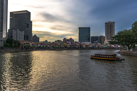 16 January 2017: Tall buildings of downtown reflecting in the Singapore river at twilight while a tourist boat is crossingのeditorial素材