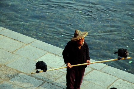 An old man holding bamboo stick with birdsのeditorial素材