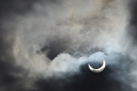 Partial solar eclipse with the cloudsの写真素材