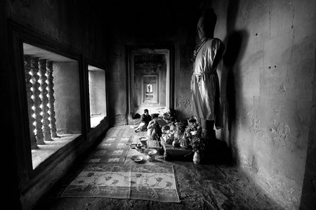 Black and white photo of a Buddha statue among worshipers in the Angkor Wat temple, Cambodiaのeditorial素材