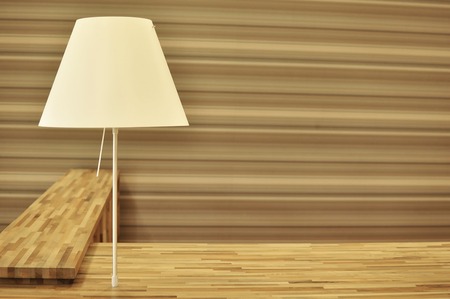 Frontal view of an L shaped reception desk, striped with different colors of wood elements, with a table lamp.の写真素材