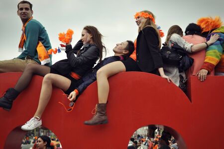 April 2014, Museumplein, Amsterdam. Young people sitting on top of the Iamsterdam street sign at the King's day festivities.のeditorial素材